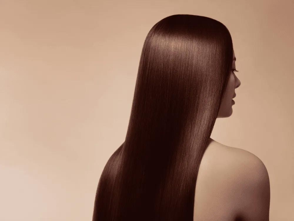 A side-profile view showcases long, smooth, glossy dark brown hair against a neutral background, highlighting healthy hair growth and shine.