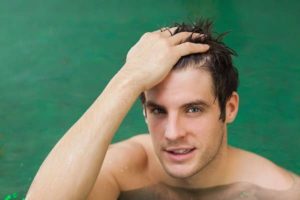 Man running his hand through his hair while relaxing in the water.