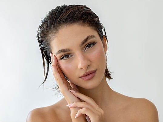 Woman with short dark hair resting her face against her hand.