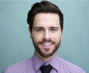 Headshot of a smiling man with short dark hair and a neatly trimmed beard.