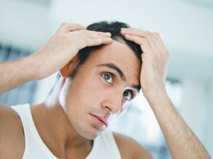 Man examining his hairline while looking in a mirror.