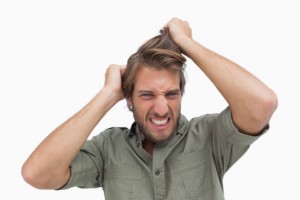 Man pulling at his hair in frustration, illustrating hair loss concerns.