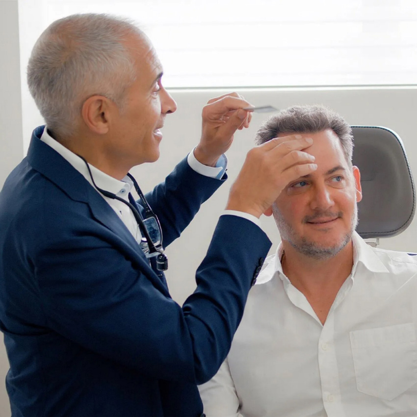 Dr. Jeffrey Epstein, Miami board-certified facial plastic surgeon, examining a patient's hairline during a consultation.