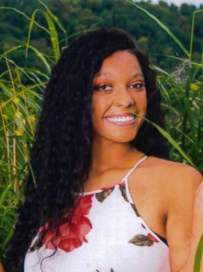 Young woman smiling outdoors showcasing long hair following hair restoration treatment.